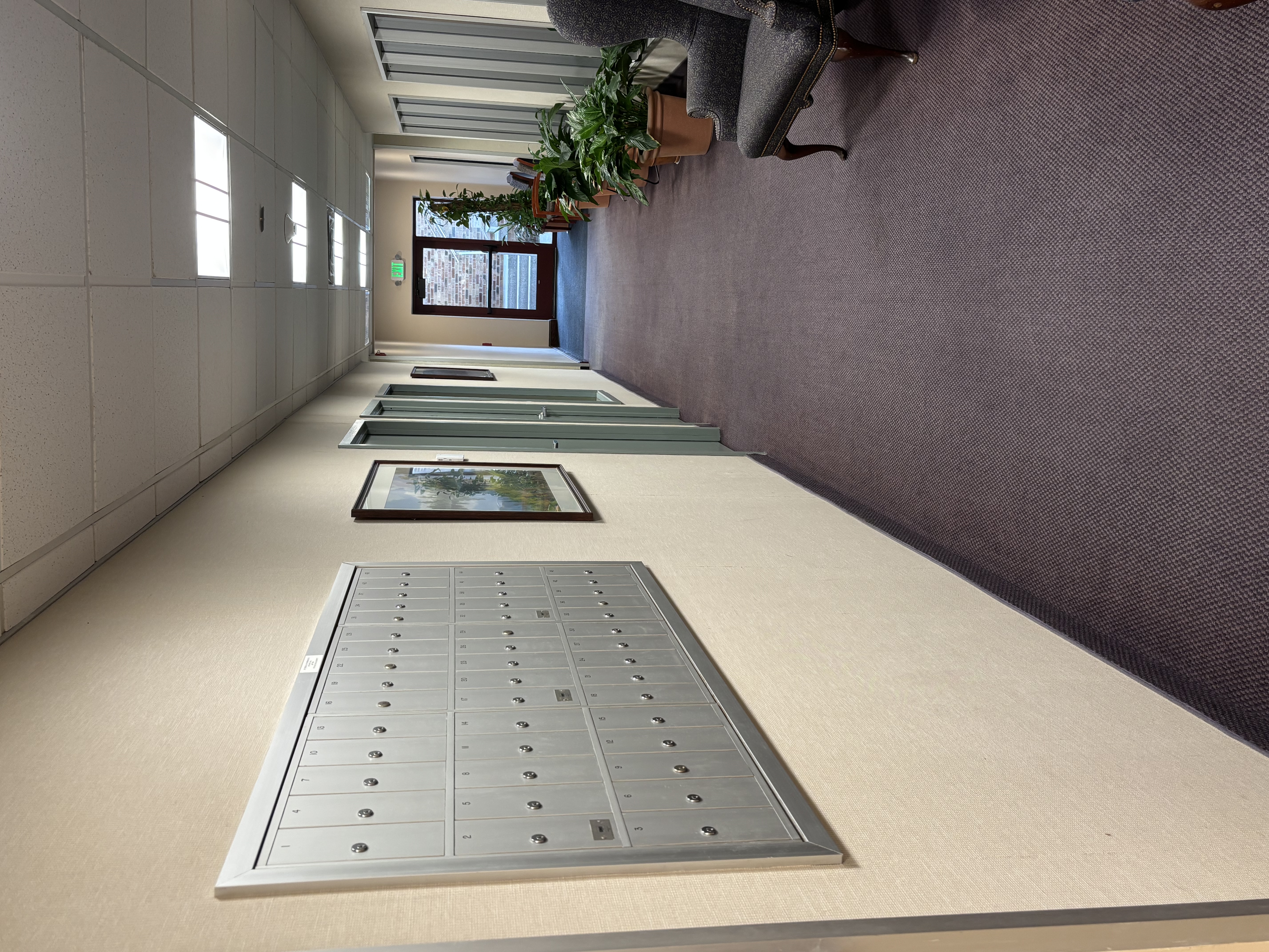 Mailboxes, seating and plants in a hallway.